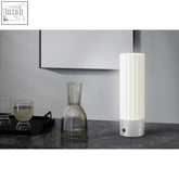 A sleek white led table lamp with vertical ridges and a premium brushed steel base perfect for any desk