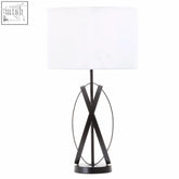 Black cross lamp with an oval geometric base and a white linen shade perfect for modern table lighting