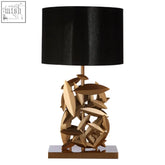 Zilla table lamp with a black drum shade and a gold table lamp base of overlapping fish-shaped pieces