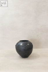 Dark gray ceramic zulu pot from south africa with rounded body and decorative beaded pattern around the rim