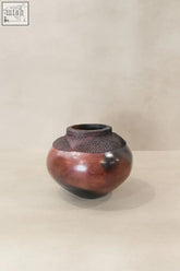 Handcrafted zulu pot from south africa with glossy reddish brown ceramic and dark woven band around the neck