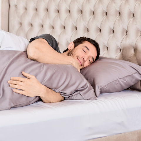 A man sleeps peacefully on a bed with soft gray 100% organic bamboo silk pillowcases in a 2 pack