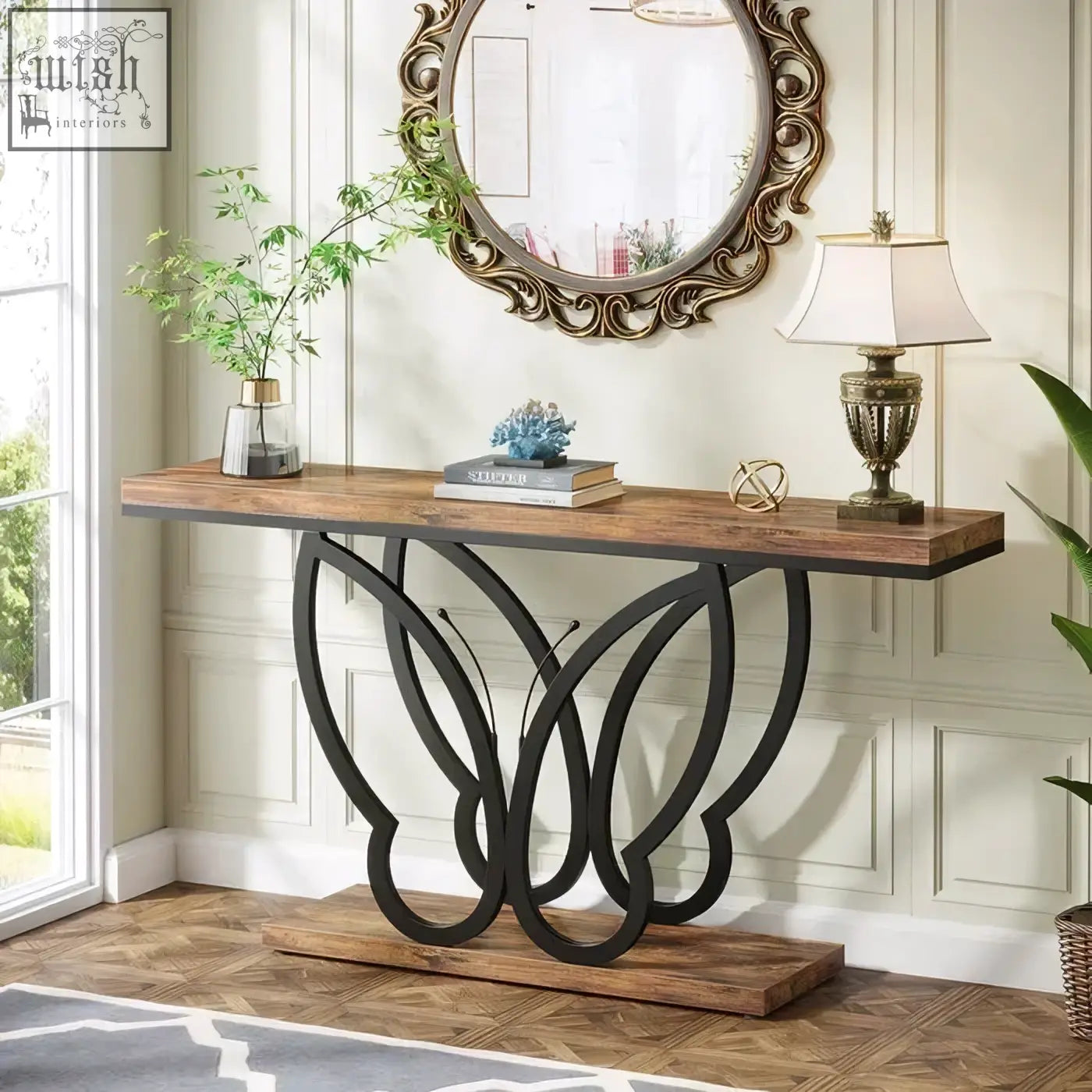 Rustic 140cm console table with wood top and black butterfly metal frame holding books lamp and plants