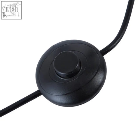 Black circular power switch with textured button attached to cable for height adjustable revolution tripod floor lamp