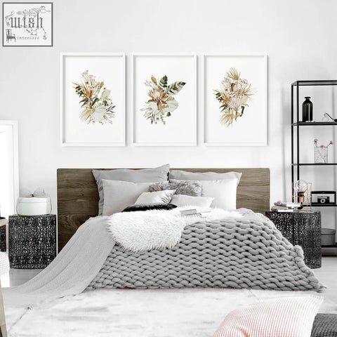 Gray knitted throw blanket with chunky weave draped on bed beneath set of 3 framed wall art prints