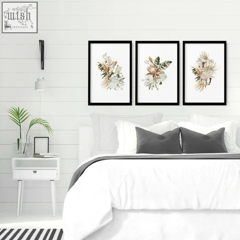 Three black-framed botanical wall art prints featuring delicate dried flowers perfect as framed wall art above bed