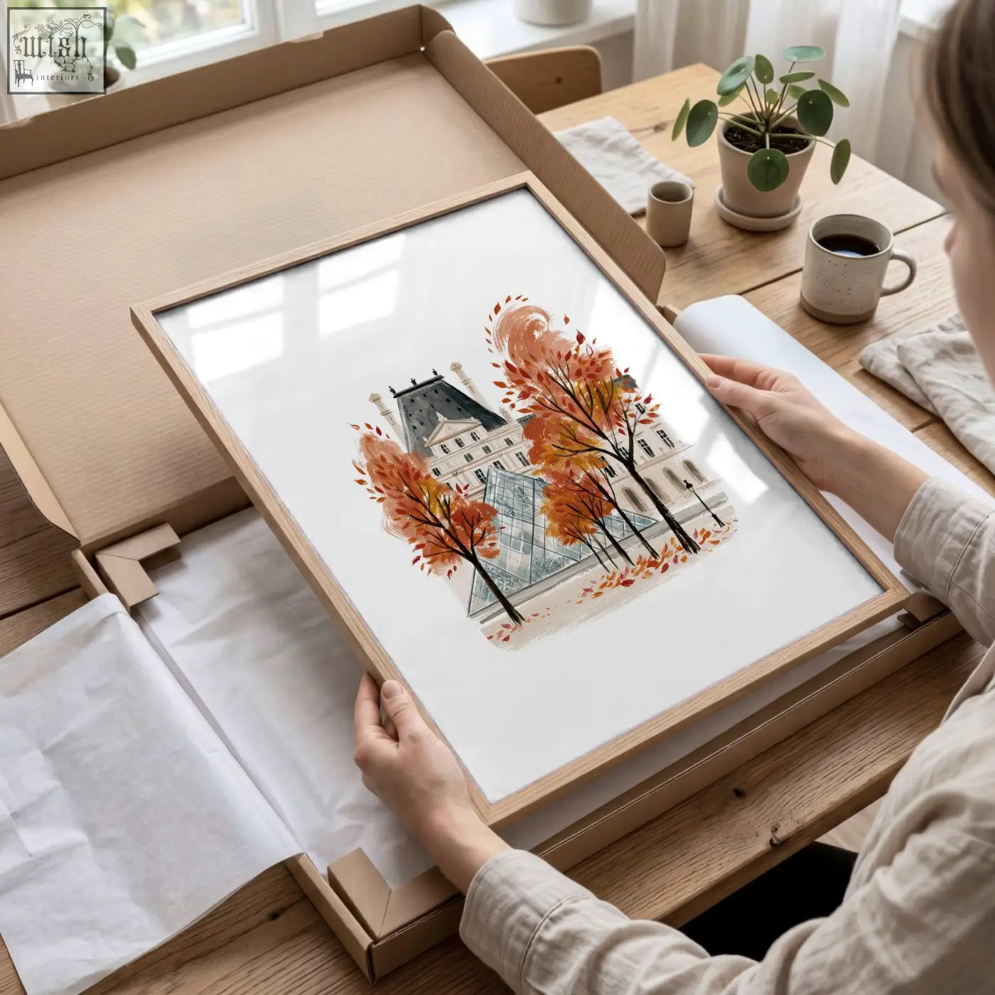 A framed watercolor art print of a paris building with autumn trees in a light wood frame perfect for dining room decor