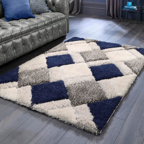 A plush navy geometric shaggy rug with a 3d geometric patchwork design in navy blue cream white and gray tones