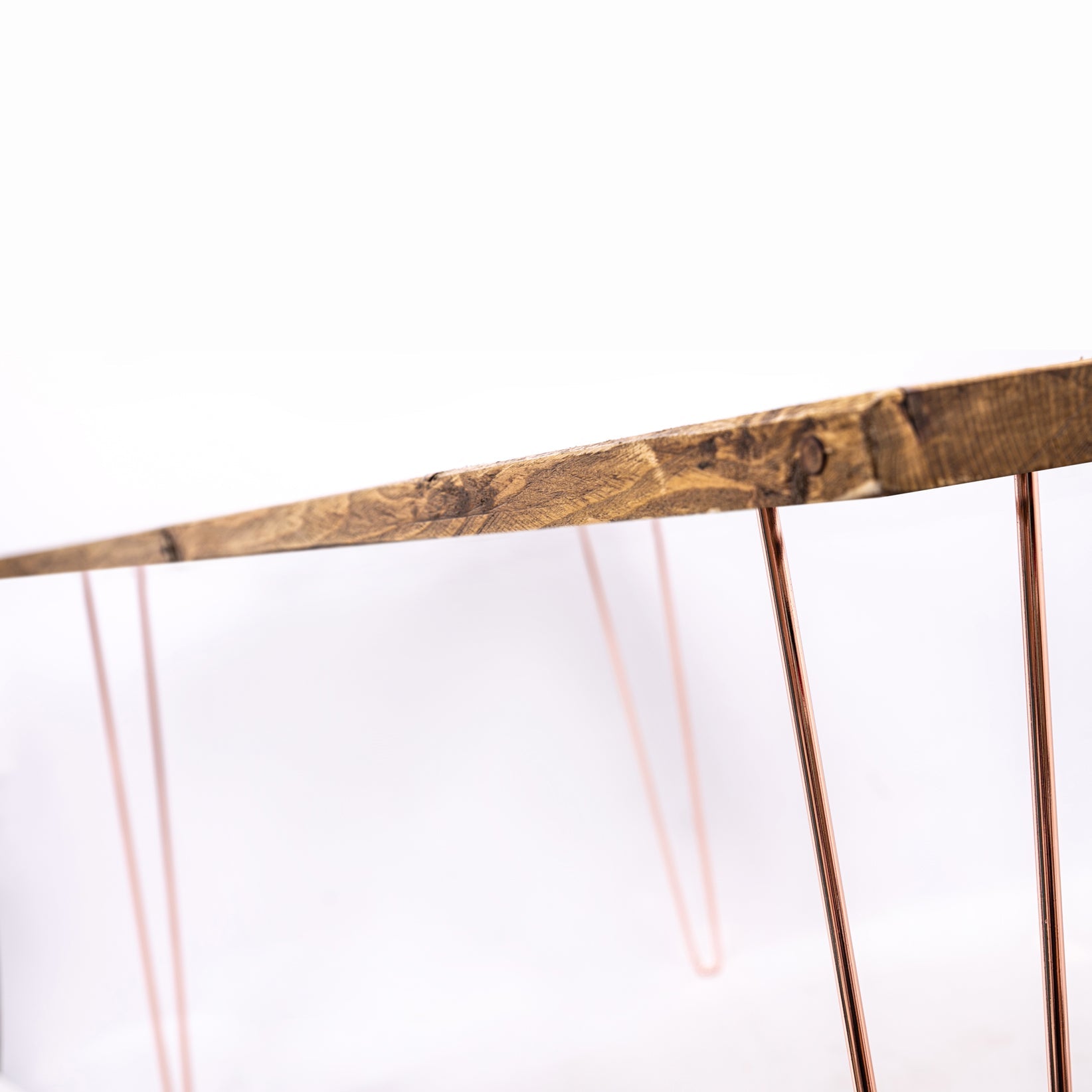 A rustic wooden dining table with warm brown finish and rose gold steel hairpin legs perfect for furniture care kit use