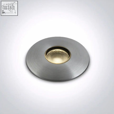 Circular recessed led inground light with brushed metallic finish and gold toned textured lens for path illumination
