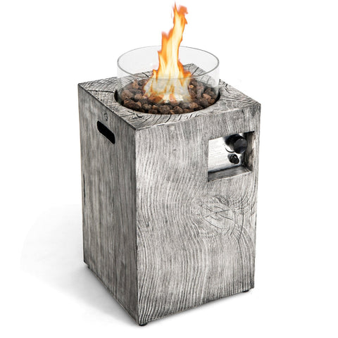 Gray wood-textured 8.79 kw propane gas pit table with glass wind guard and glowing flames over dark pebbles