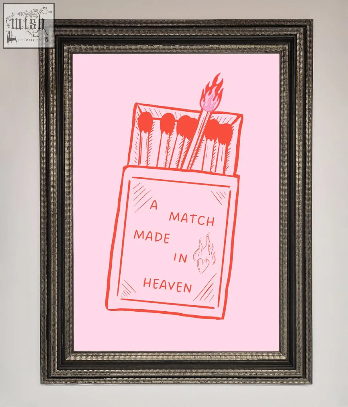 Pink framed wall art featuring a red line drawing of an open matchbox with a flame and the text a match made in heaven framed wall