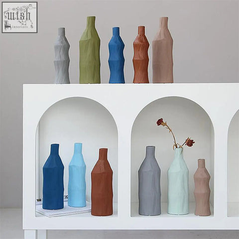 A set of two fresh ceramic vases in muted earth tones and pastels with textured faceted surfaces