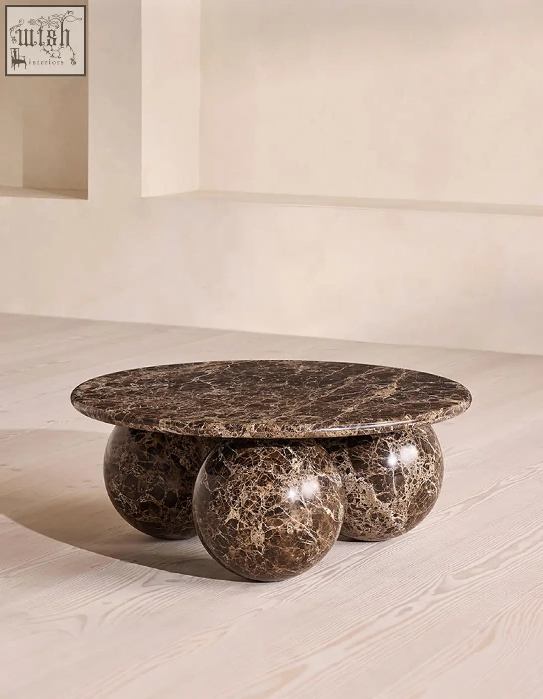 Abdurrahman round coffee table is a brown marble coffee table with a round top and three spherical legs