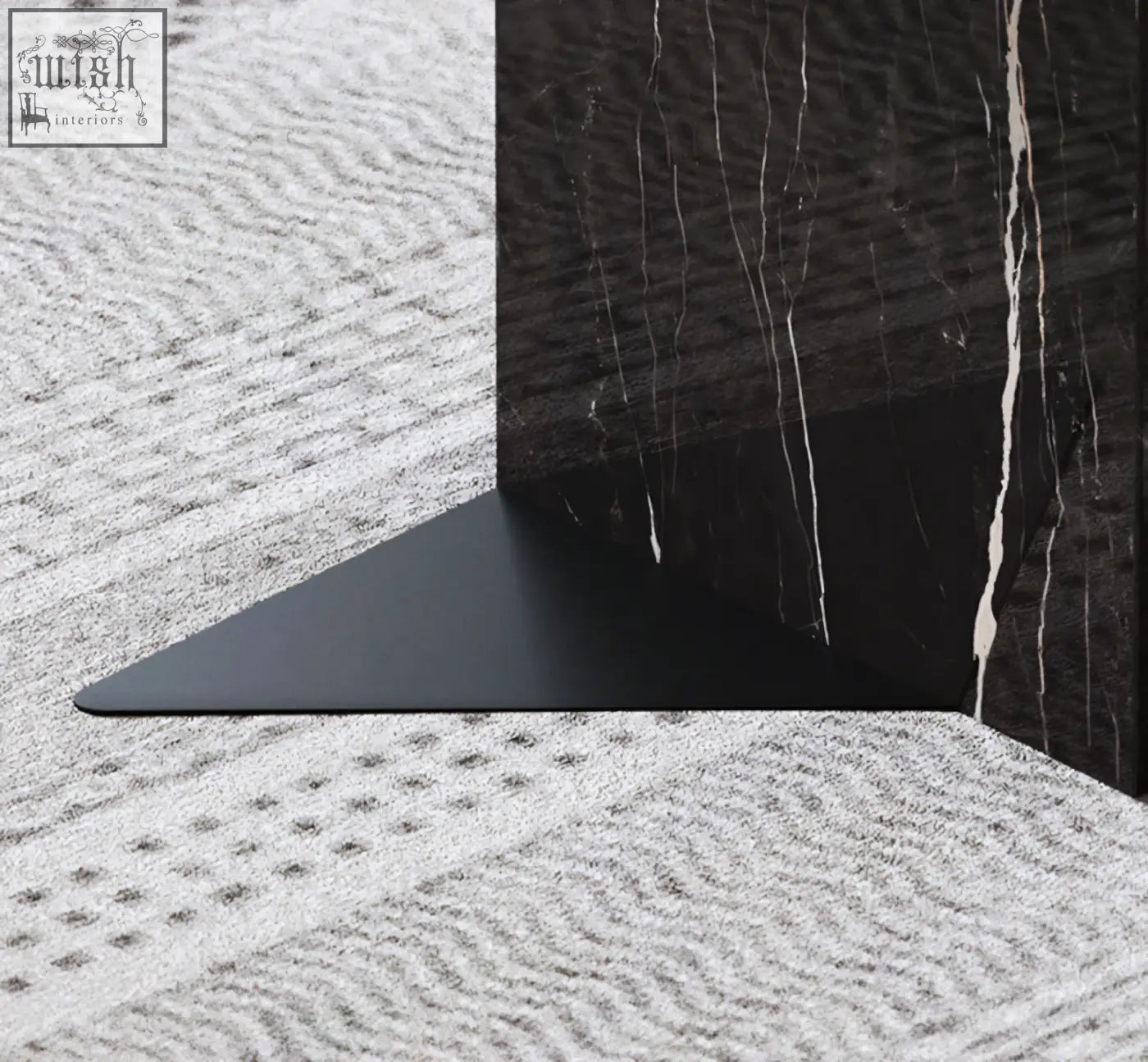 Black triangular metal bookend with matte finish resting on dark marble surface in aberdeen coffee table set