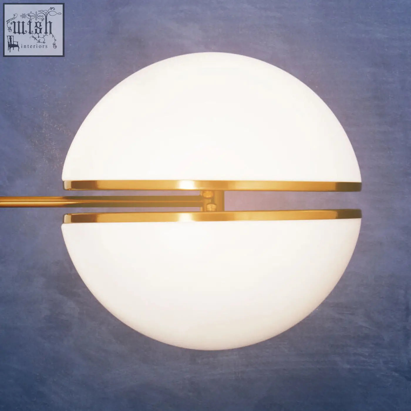 Abira brushed brass ball wall light with a frosted white glass shade and polished brass wall accents for modern style