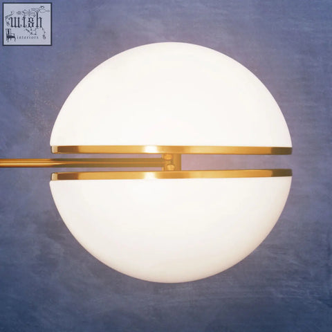 Abira brushed brass ball wall light with a frosted white glass shade and polished brass wall accents for modern style