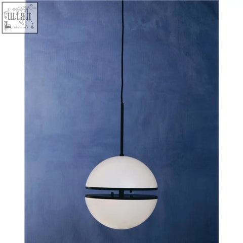 A sleek white spherical matt black pendant light with a black band suspended by a cord against a blue wall