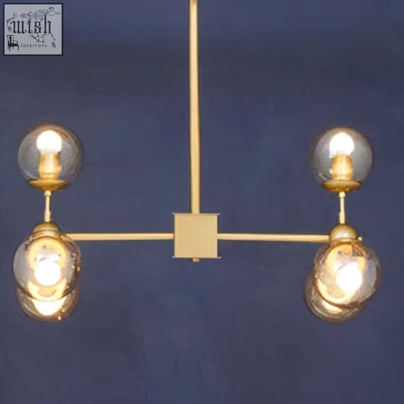 Gold-toned abira six arm pendant light with four spherical glass bulbs on a minimalist metal frame