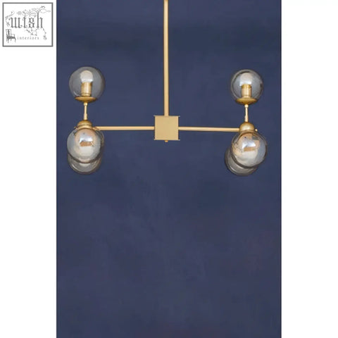 Gold-toned six arm pendant light with four glass globes on a minimalist geometric frame perfect for modern spaces