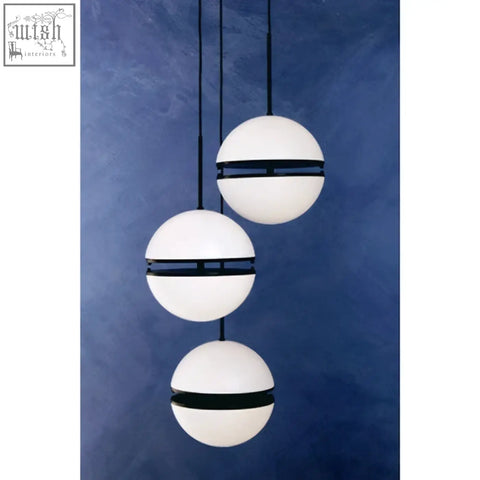 Abira three ball matt black pendant light with three white glass balls and black bands against a blue wall