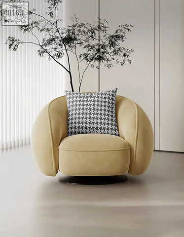 Cream-colored velvet abreu swivel accent chair with round armchair design and black-and-white houndstooth pillow