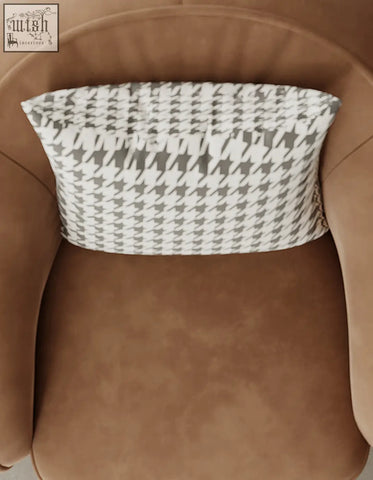 A rectangular gray and white houndstooth cushion on a tan abreu swivel accent round armchair