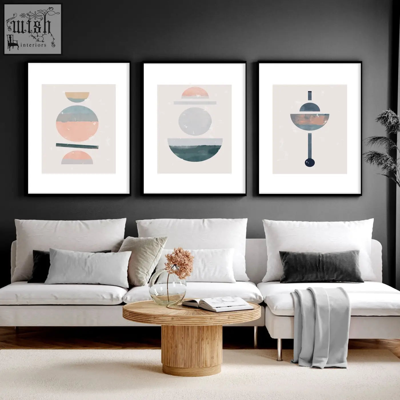 Three framed abstract art prints with pastel and earth-toned shapes hang above a white sofa in a living room