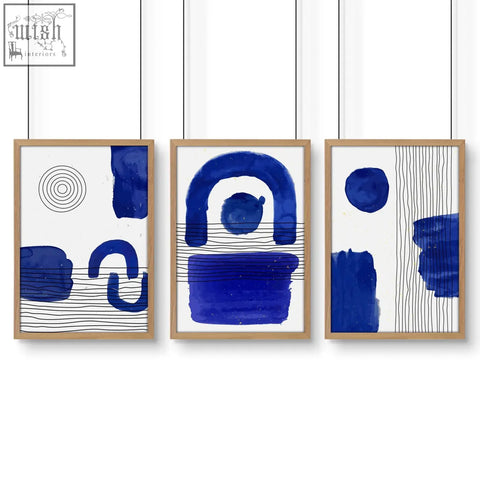 Set of 3 abstract art prints with bold blue brushstrokes and black lines in light wood frames for wall art