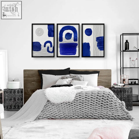 Set of 3 abstract wall art prints with bold blue brushstrokes in sleek black frames for modern wall art