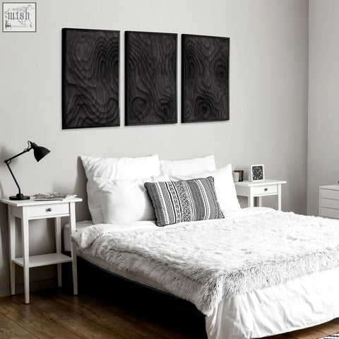 Three black wood grain wall art panels with raised textured patterns in dark charcoal abstract topographic wave design