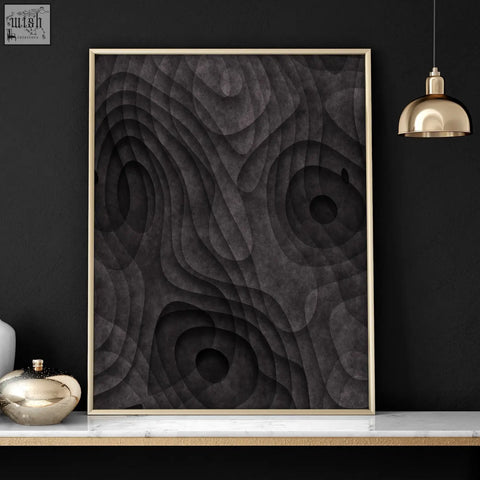 A modern abstract artwork print with dark charcoal topographic wave patterns in a sleek gold-toned frame