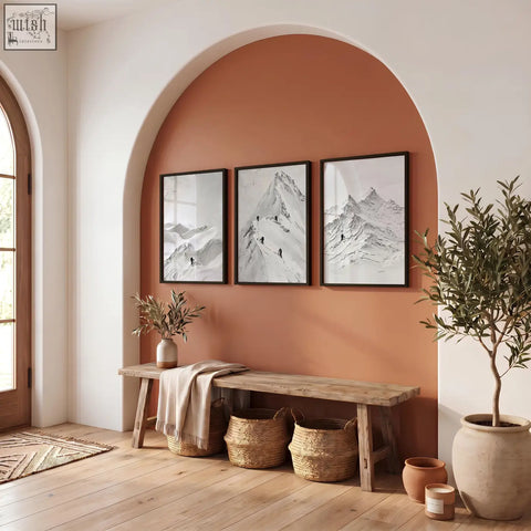 Three black-framed abstract mountain art prints with white snow hang above a rustic wooden bench as wall art set of 3