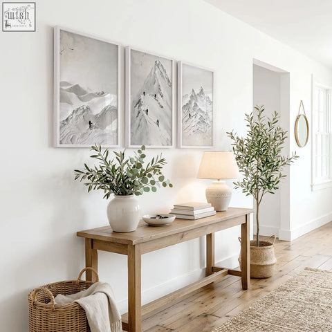 A white ceramic vase with a smooth rounded body and narrow neck shown with abstract mountain wall art prints