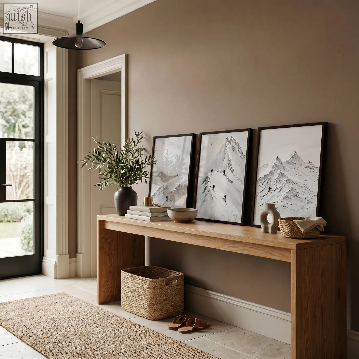 A minimalist wooden console table with natural finish below abstract mountain art white snow climbers wall art prints set of 3
