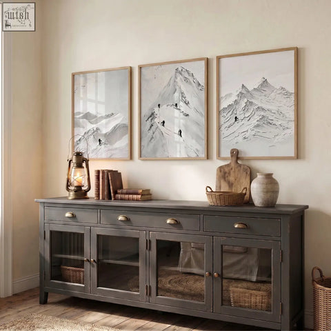 Dark gray wooden sideboard with glass cabinets and brass handles below abstract mountain art white snow climbers wall art set