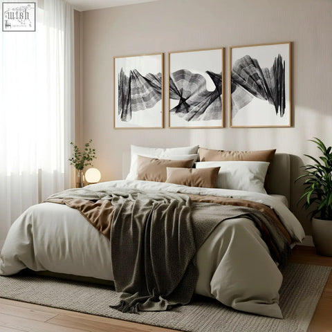 A cozy bed with soft beige and brown linens and a dark green throw featuring an abstract painting art print set of 3