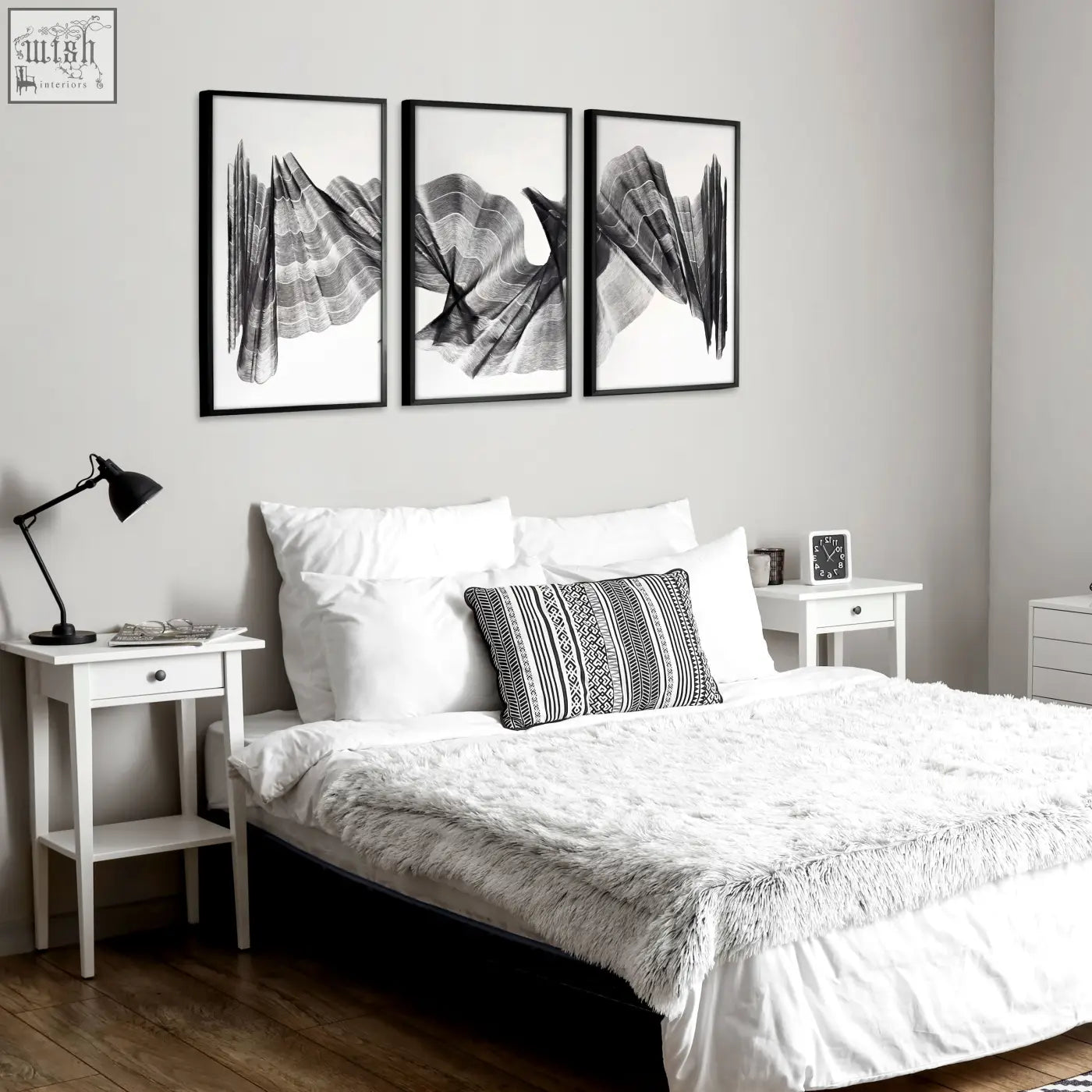 Three black-framed abstract painting art prints with flowing charcoal textured wave patterns hang above the bed