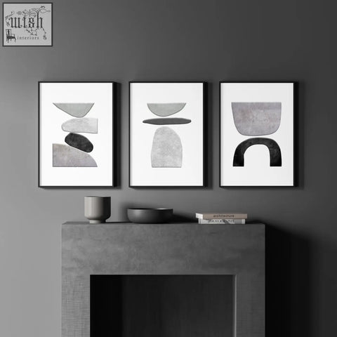 Three minimalist black framed wall art prints with layered geometric shapes in muted gray and charcoal tones on white background
