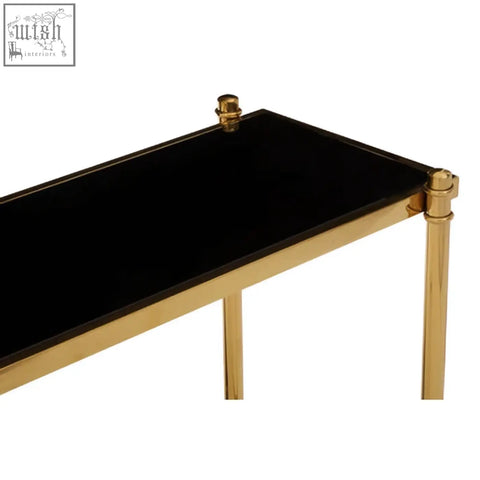 Ackley gold console table with black glass top and gold-toned metal legs featuring decorative finials