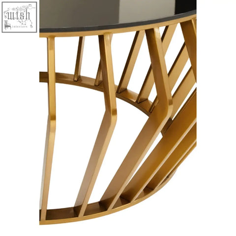 Ackley gold round coffee table with gold-toned metal frame and sleek black glass top with geometric legs