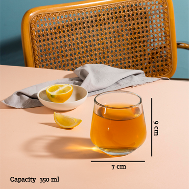 A clear crystal large tumbler with straight sides and rounded base filled with amber liquid in ada set of 4