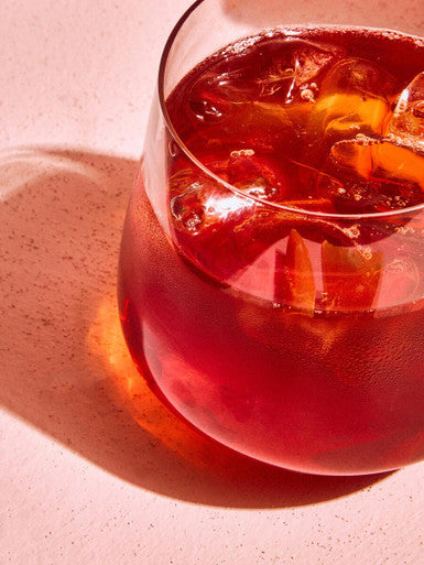 A clear glass crystal large tumbler filled with vibrant red beverage and ice cubes from ada set of 4