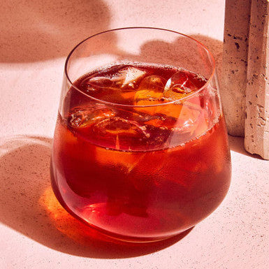 A clear glass crystal large tumbler filled with a deep red drink and ice cubes from ada set of 4 large tumblers