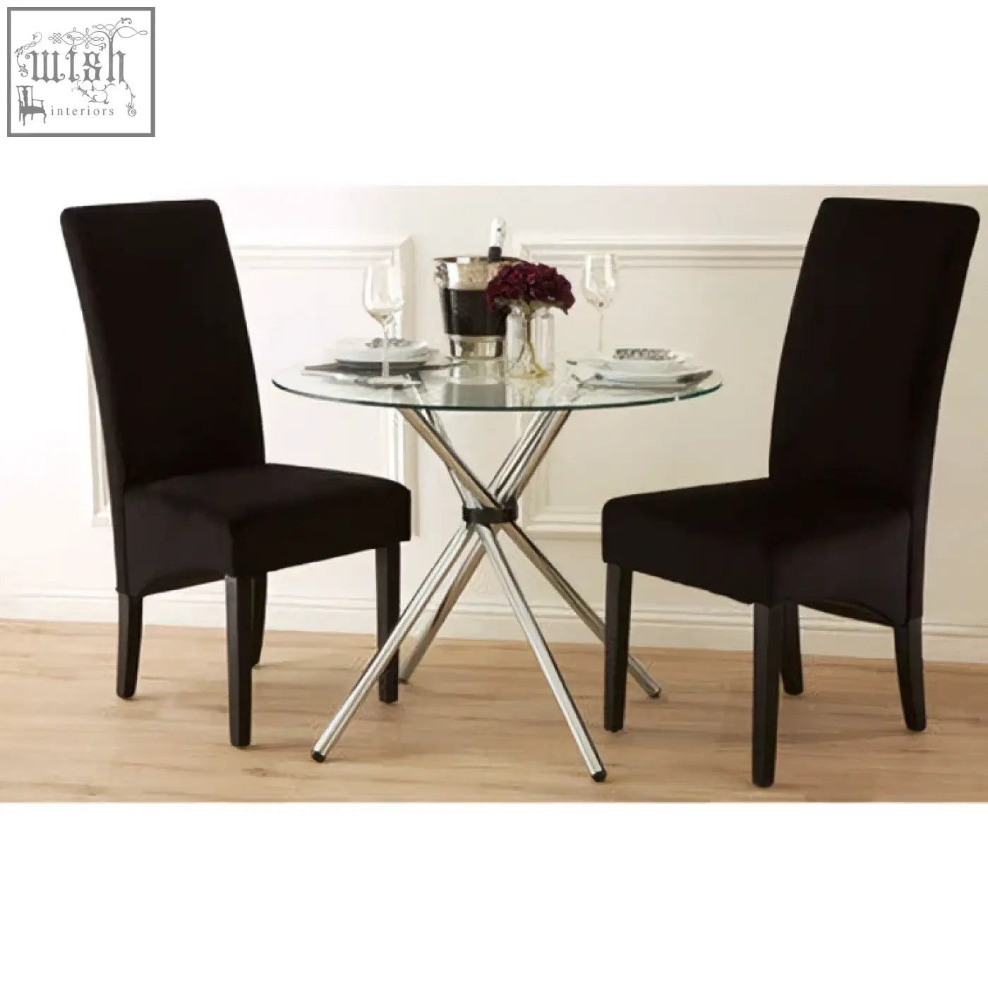 Black velvet dining chairs with sleek chrome cross base and four angular legs paired with afton round dining table with glass top
