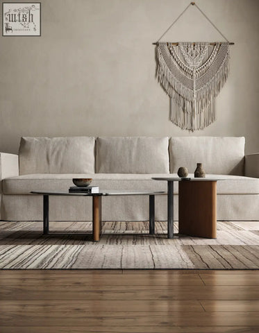 Beige macramé wall hanging with intricate woven patterns and long fringe shown with agatha nesting coffee table setup
