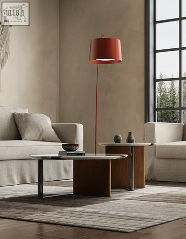 A sleek red shade floor lamp with metallic stand next to agatha nesting coffee table mable and nesting coffee table
