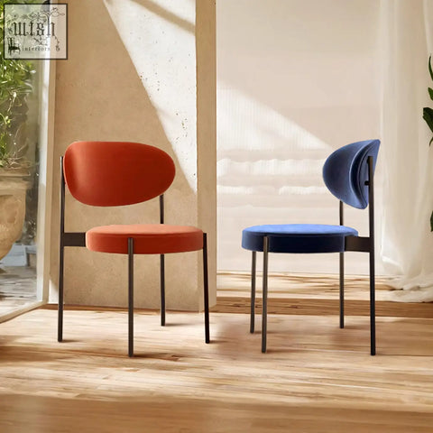 Modern minimalist ahmed dining chairs with sleek black metal frames and plush orange and navy blue velvet seats