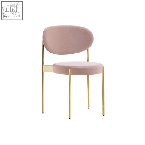 A modern ahmed dining chair with soft blush pink velvet seat and backrest supported by slender gold metal legs