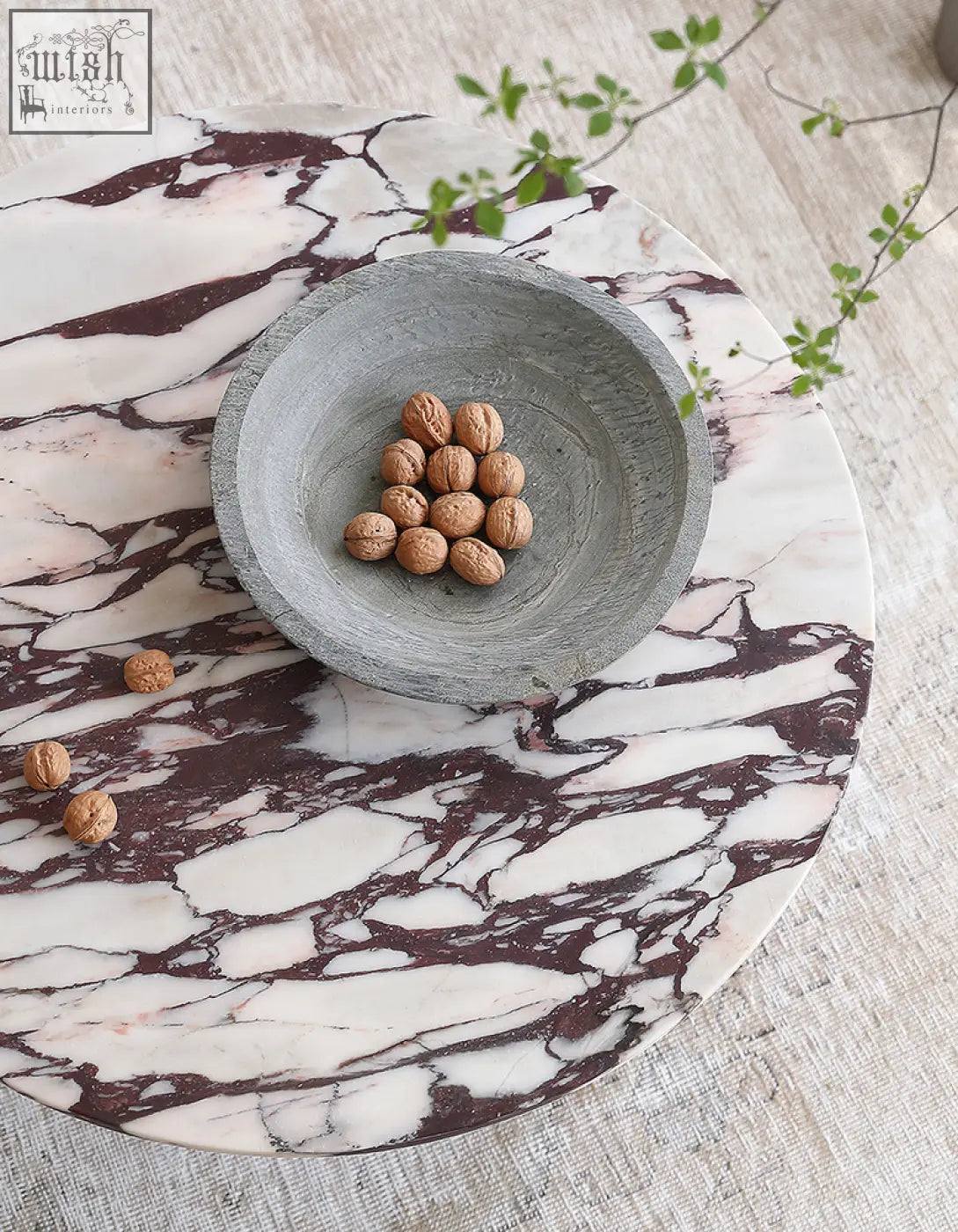 Aiko coffee table round marble with a gray stone bowl filled with walnuts on a white and burgundy marble tray stone coffee table